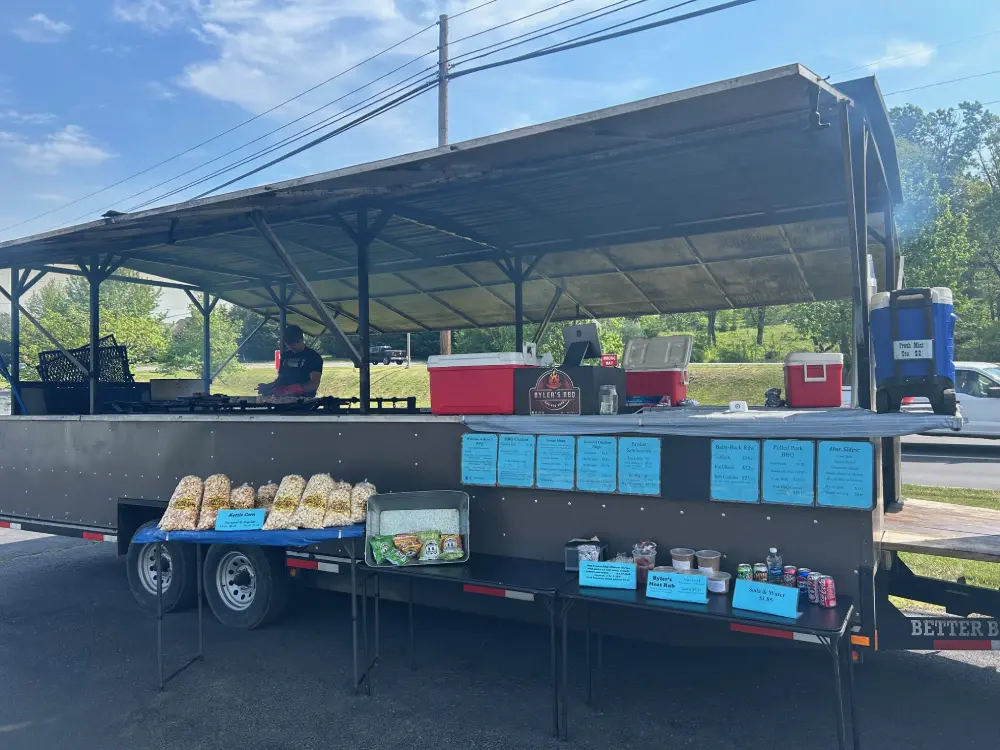 Byler's BBQ trailer set up, featuring popcorn, drinks, and smoked meats ready to serve.